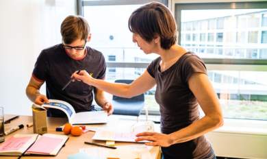 Zwei Frauen die sich Unterlagen auf einen Tisch anschauen